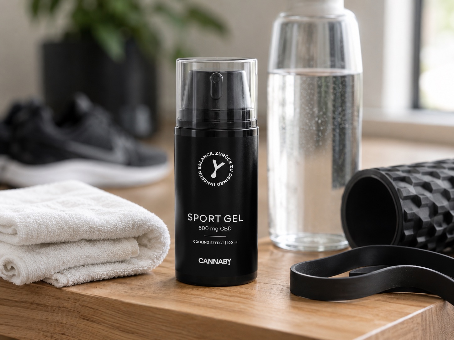 CANNABY CBD Sportgel neben Sporthandtuch und Trainingsausrüstung