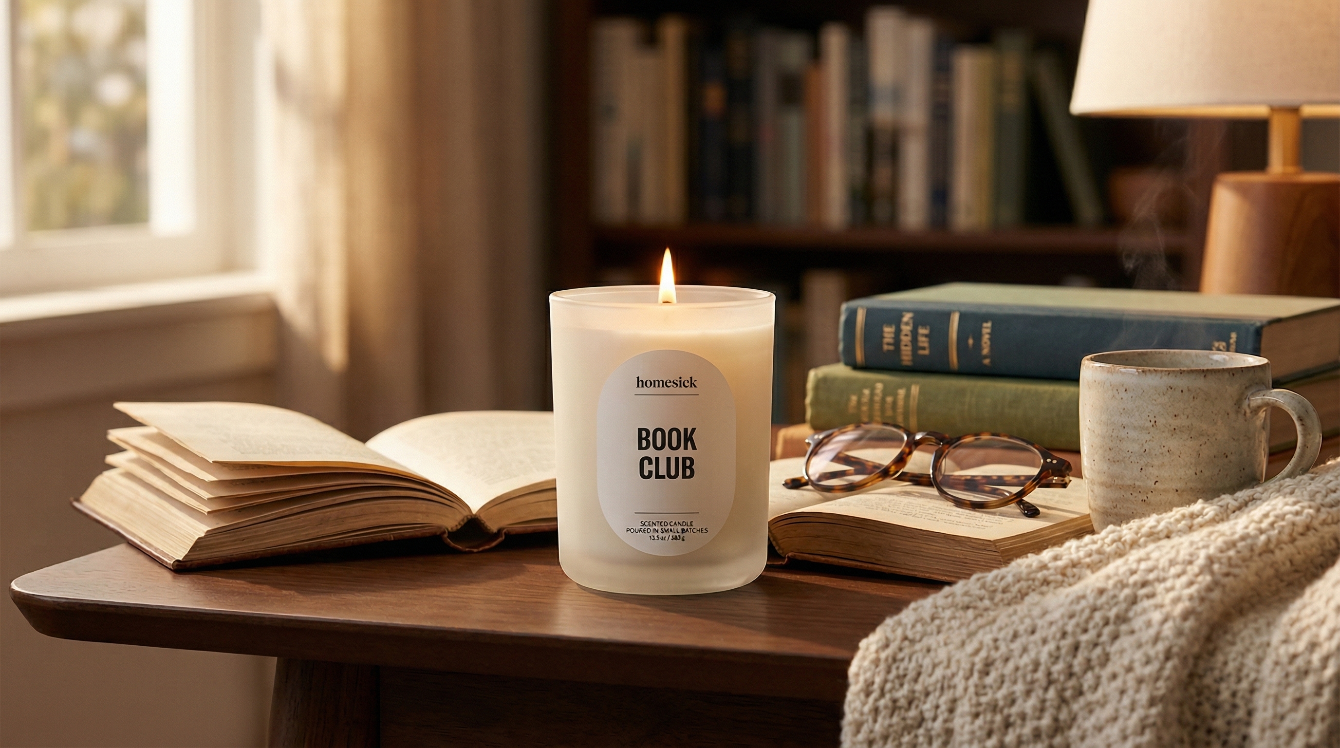 Homesick Book Club candle on a cozy reading table with books
