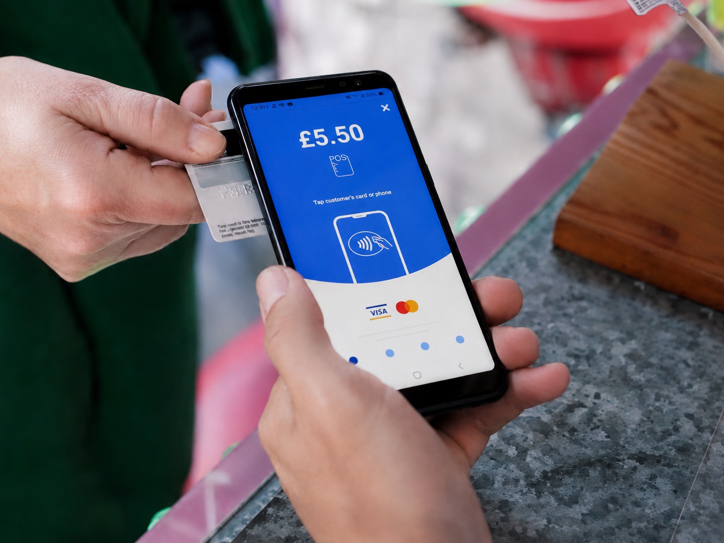 Small business owner accepting a contactless payment on a phone using myPOS Tap to Pay